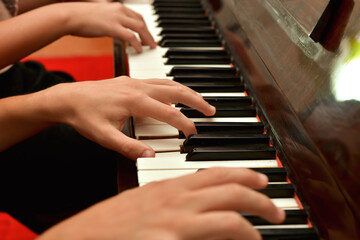 Obraz premium A girl and a guy play the piano in four hands. Rehearsal and training at a music school.