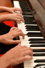 Fototapeta premium A girl and a guy play the piano in four hands. Rehearsal and training at a music school.