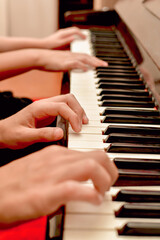 Fototapeta premium A girl and a guy play the piano in four hands. Rehearsal and training at a music school.