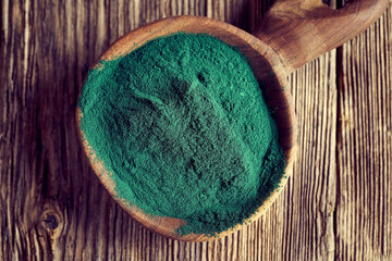 Spirulina powder on a spoon, top view. Healthy nutrition.