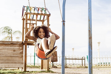 happy and smiling african american girl playing on swing. fun and recreation concept.