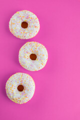 White Donuts with pink background. Donuts with sprinkles