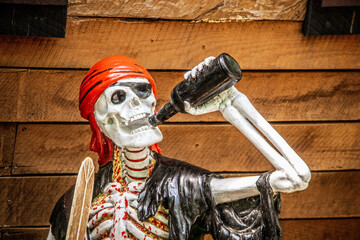 Grungy painted and glued together bloody skeleton pirate drinking beer with boat hull background...