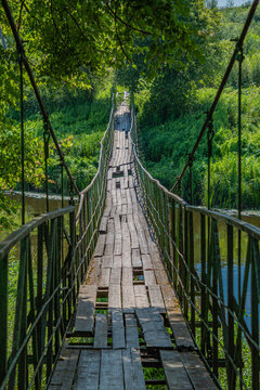 A cable bridge across the river with broken boards. © Ieva