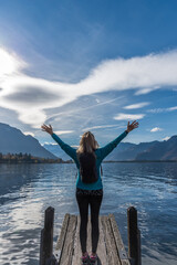 Unrecognized woman raising her arms and enjoying the views of the mountains and the lake.