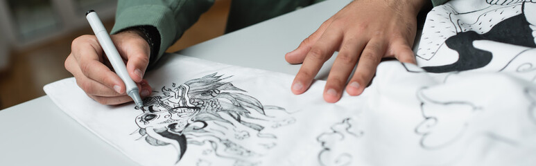 partial view of artist drawing on kimono in fashion atelier, banner