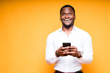 Handsome happy african american man holding phone in hand and smiling looking at camera