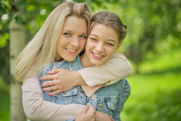 Fototapeta na wymiar happy mother with her daughter hugging a teenager in the summer. Caring happy mother enjoy day with teenage girl child, laugh have fun. Mother giving her daughter advice.