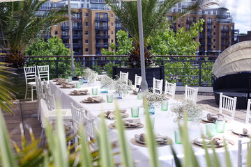 Luxuriant Table Setting on city rooftop terrace in summer with palm leaves ready for fine dining