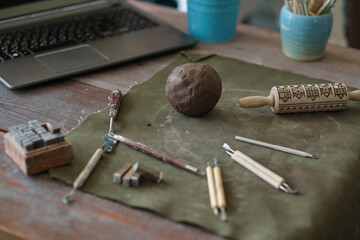 clay and tools are on the table in front of the laptop. ceramics online training concept. video tutorials for hobbies. Pottery tools