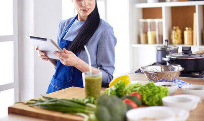 Young woman using a tablet computer to cook in her kitchen