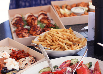 Bowl of chips or fries as the central focus on a table of buffet foods served at an outdoor garden party.