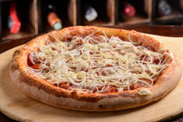 Pepperoni sausage pizza with onion on a wooden board. Brazilian pizza.