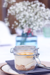 Very posh Lemon Cheese Cake Served in a decorative glass jar, on a table at an outdoor event with table decorations