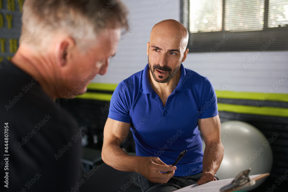 Wall mural male personal trainer , physical health consultation with elderly man