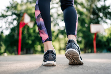 Plakat Closeup view on Young girl woman legs wearing sport leggings and shoes sneakers during exercising at stadium outdoors. Female person doing fitness workout outside
