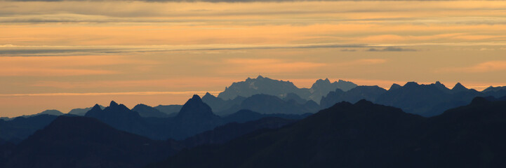 Bright lit yellow morning sky over Mount Grosser Mythen, Saentis and other mountains in the Swiss Alps.