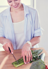 Young woman cutting vegetables in kitchen at home.