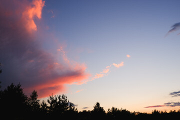 Background. Dramatic sunset. Red-orange clouds against the blue sky. Sunset orange red yellow pink clouds against blue sky texture