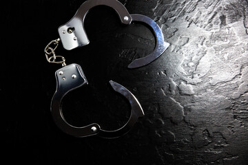 Police metal real handcuffs on the black background. Crime and robbery, prison concept.