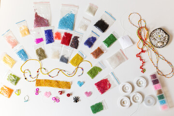 Creative, bright and colorful beads on the white table. Handicraft workplace. Beautiful diy jewelry...