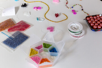 Creative, bright and colorful beads on the white table. Handicraft workplace. Beautiful diy jewelry and calming stress relieving hobby and activity