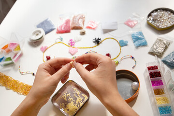 Beading workplace with hands in the process of handicraft. Beautiful diy jewelry and calming stress...
