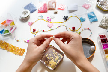 Beading workplace with hands in the process of handicraft. Beautiful diy jewelry and calming stress...