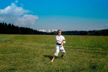 teenage girl training karate kata outdoors, prepares to perform downward block gedan barai in zenkutsu dachi stance