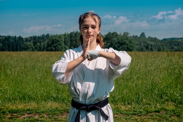 teenage girl training karate kata outdoors, greetings oss © Evgeny