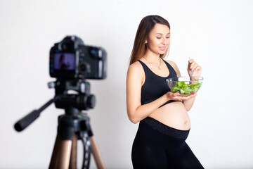 A pregnant woman blogger records a video on camera about proper nutrition during pregnancy. Sport...