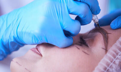 Permanent makeup for eyebrows. Closeup of beautiful woman with thick brows in beauty salon.