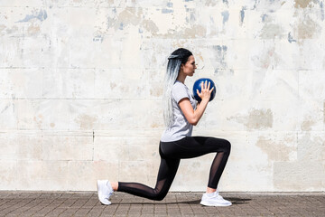 Woman with long braided hair doing fitness workout with a medicine ball. Youth, lifestyle concept