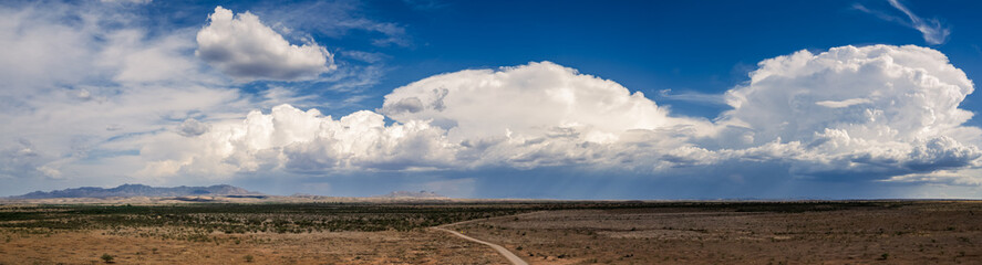 Epic aerial panorama of storm clouds over a field and dirt road in Arizona.