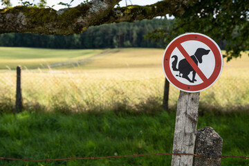 Sign in the landscape with the meaning that dogs are not allowed to make their poop in the meadow