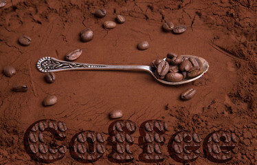 On the background of ground coffee there is a spoon with coffee beans and the inscription COFFEE...