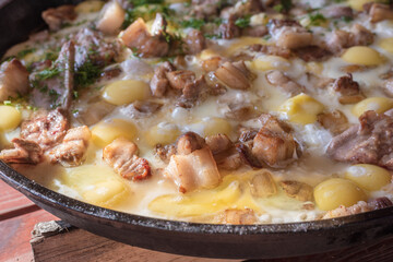 Food background. Scrambled eggs with meat and lard in a large skillet. Delicious food on the street.