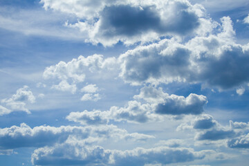 Fototapeta premium Thunderous dark dramatic cumulus white clouds against the blue sky, copy space. Blue sky with clouds, free space. The background. The sun shines through the clouds. weather.