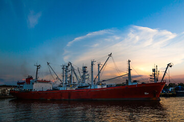 Fototapeta premium Fishing boats are moored in the seaport, against the backdrop of sunset.