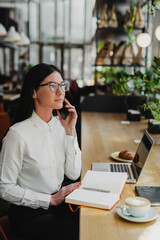 Attractive business woman sitting in a cafe with a laptop and cell phone.