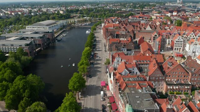 Aerial sliding footage of historic brick town houses, wide riverside street and Trave river. Luebeck, Schleswig-Holstein, Germany