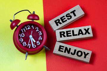 REST RELAX ENJOY - words on colorful background with alarm clock