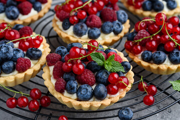 Tartlets with curd cream and fresh berries of raspberries, blueberries, red currants. Summer fruit baking. Close-up. Selective focus 