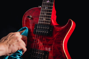 Closeup of a red shiny electric guitar body while beeing polished with a blue cloth