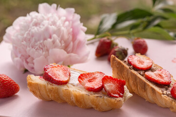 Ripe red strawberries and homemade choux pastry cake with white aquafaba souffle on pink background. Pink peony with strawberry cream cakes. Summer dessert.