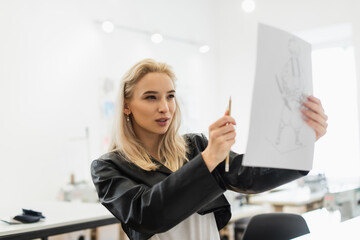 young fashion designer measuring proportions of drawing with pencil