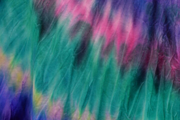 Abstract painted background. Multi-colored pattern in the shibori technique on a thin knitted fabric. Multi-color texture. batik.Textile shibori