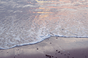 Fototapeta na wymiar Background image of ocean waves break along the shoreline with calmness along the foamy edge of sandy summer beaches