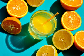 Orange and lemon juice in a glass on a blue background.
