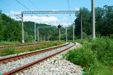 Morning landscape on the railway tracks. The sun's rays are the green grass and the rails on which...